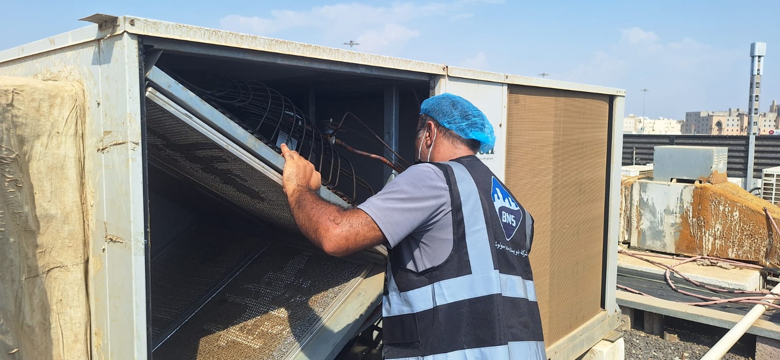 BMS technician working inside an opened rooftop air-cooled condenser cabinet