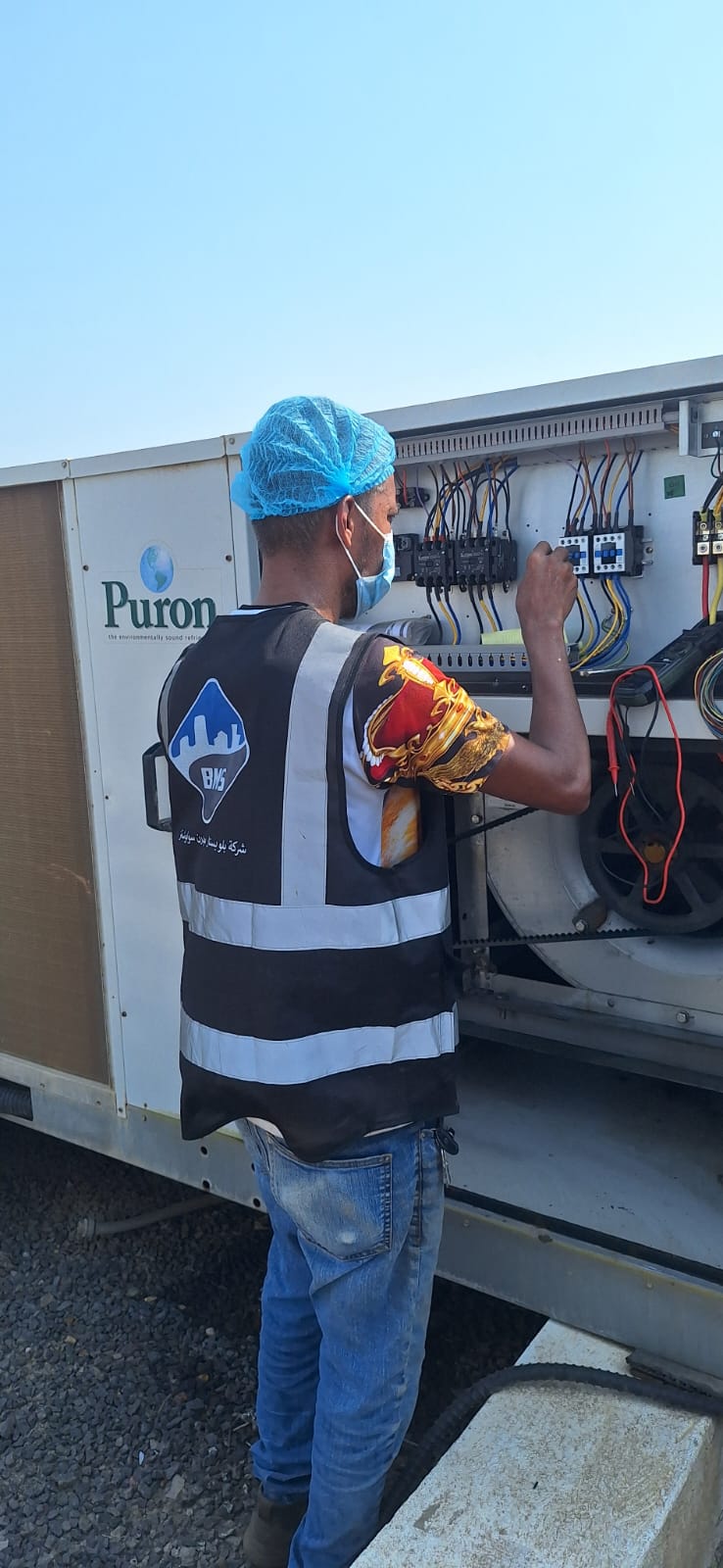 BMS technician working inside the electrical control panel of a rooftop packaged unit