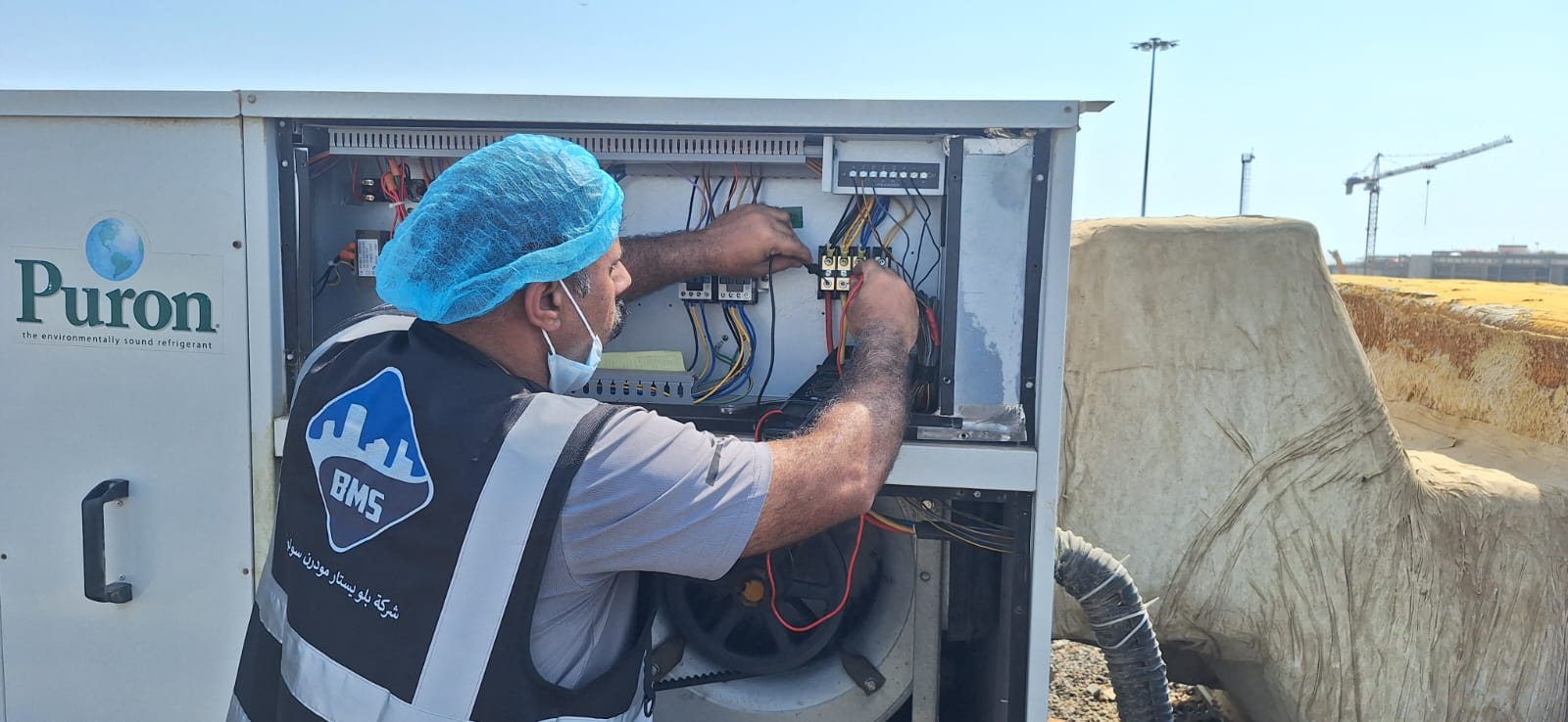BMS technician taking readings inside an open electrical control panel