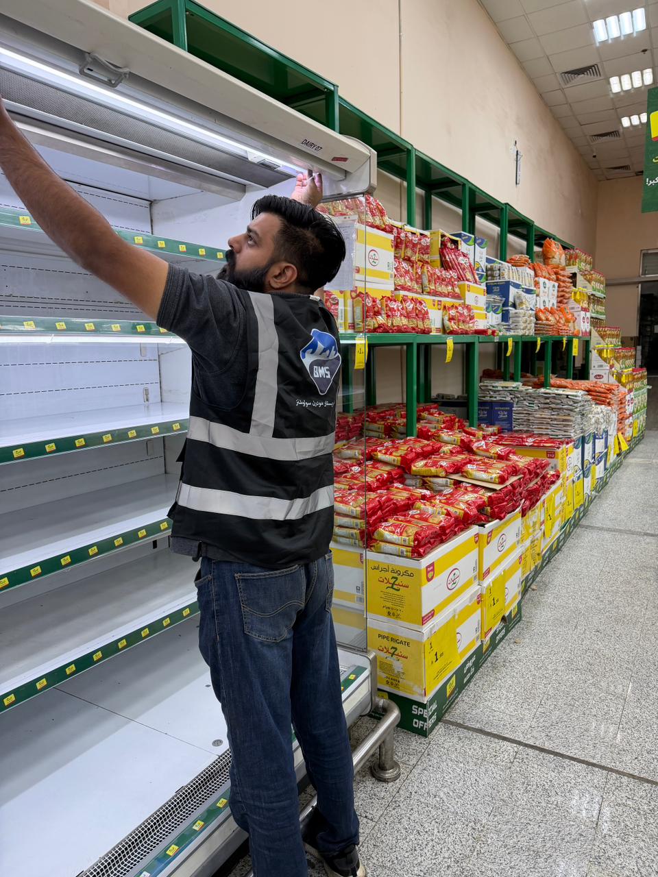BMS technician reaching up to service the canopy light strip of an emptied chiller