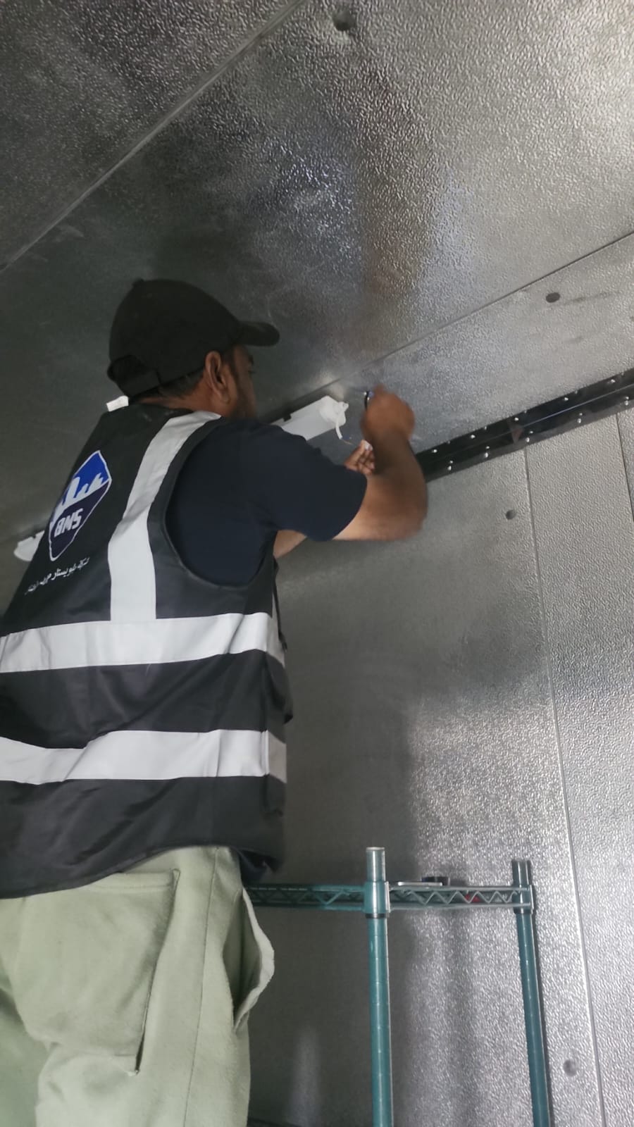 BMS technician fitting the ceiling light inside the insulated walk-in chiller at Nadah Plaza