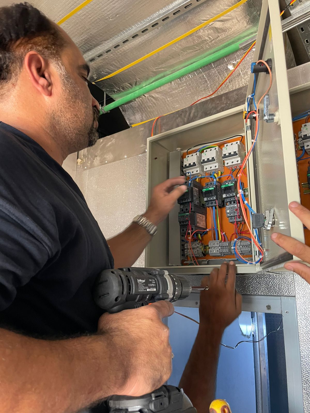 Close-up of a technician working on the contactors inside an electrical control panel