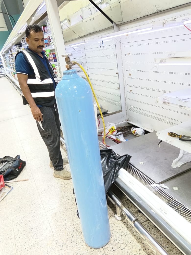 Technician pressure testing refrigeration pipework with a nitrogen cylinder
