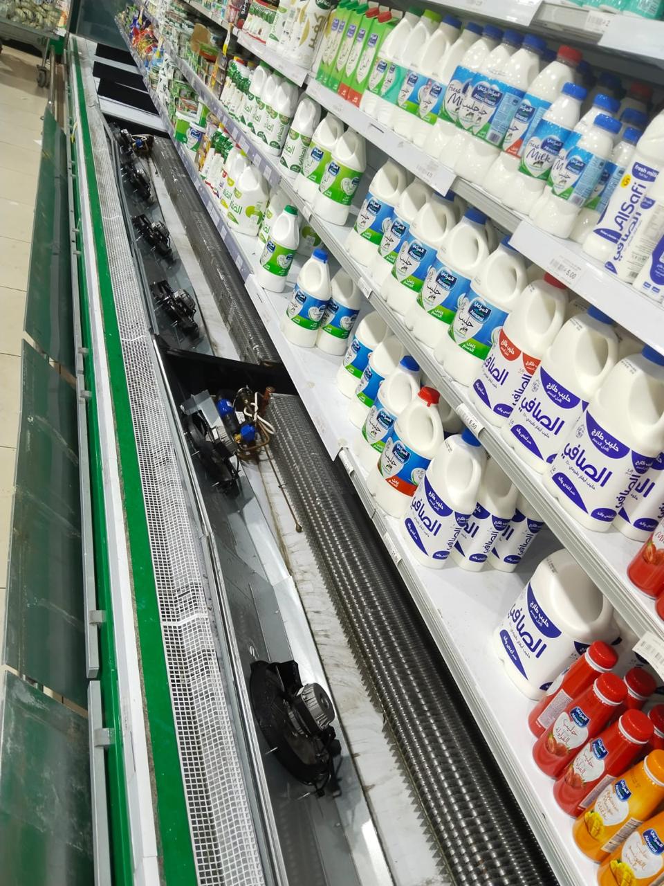Dairy multideck chiller with the base deck panel lifted to expose the evaporator coil and fan motors