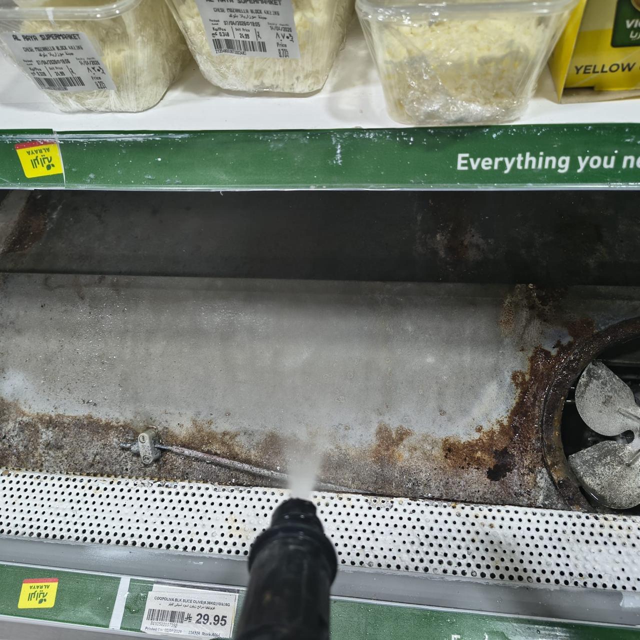 Pressure washing a heavily soiled base tray inside a deli display case