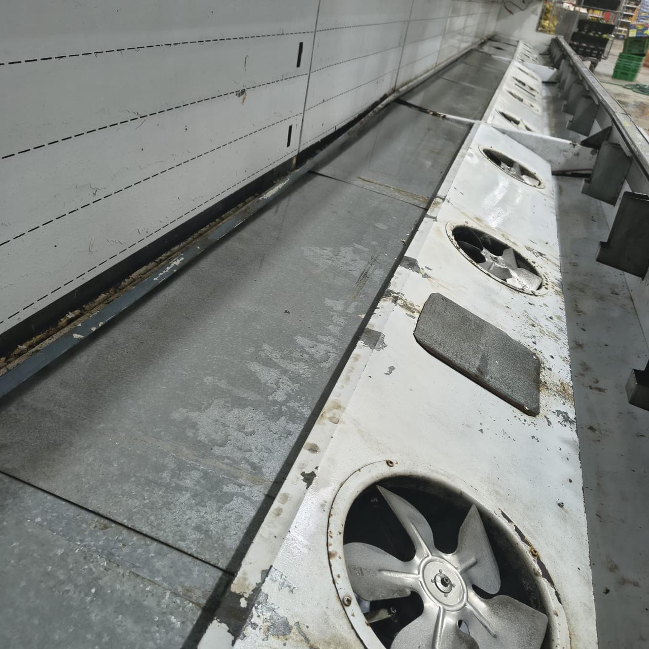 Cleaned base deck of a long display case showing a row of recessed evaporator fan housings