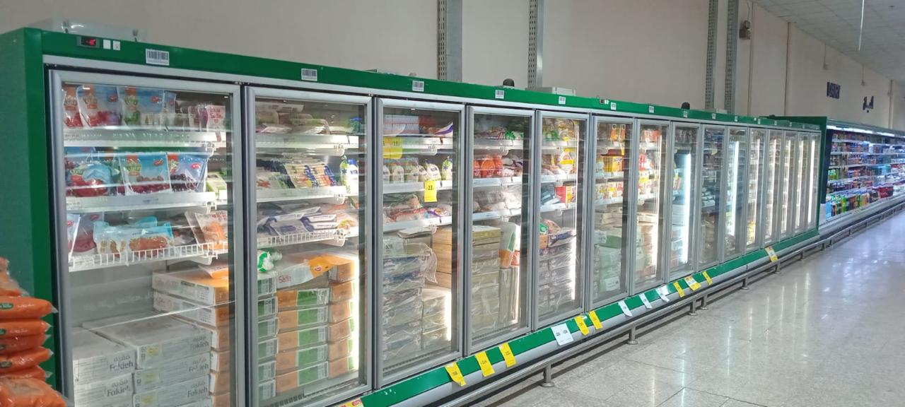 Long run of stocked glass-door freezer cabinets in a supermarket aisle