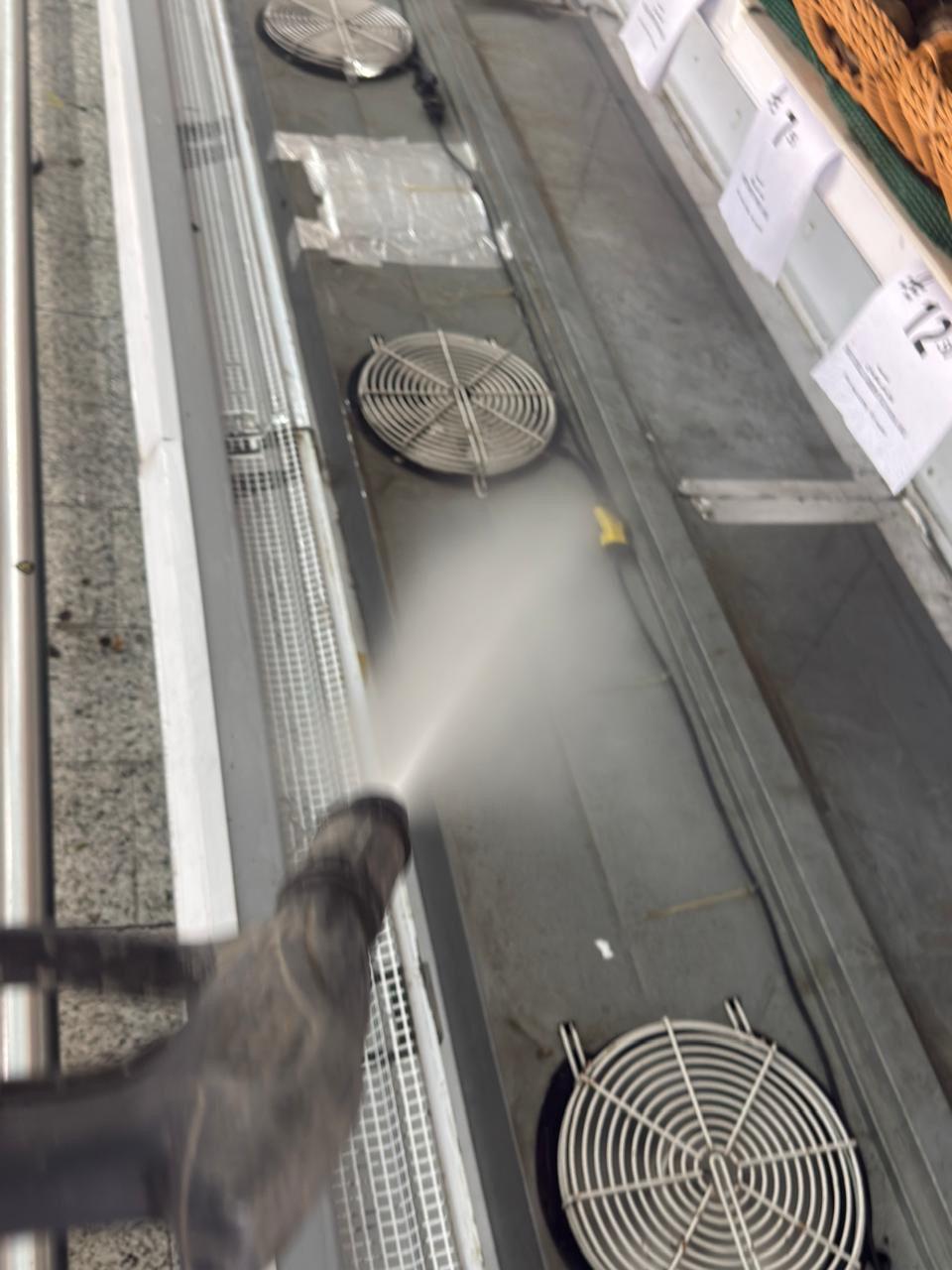 Pressure washing the interior well of an open island freezer cabinet