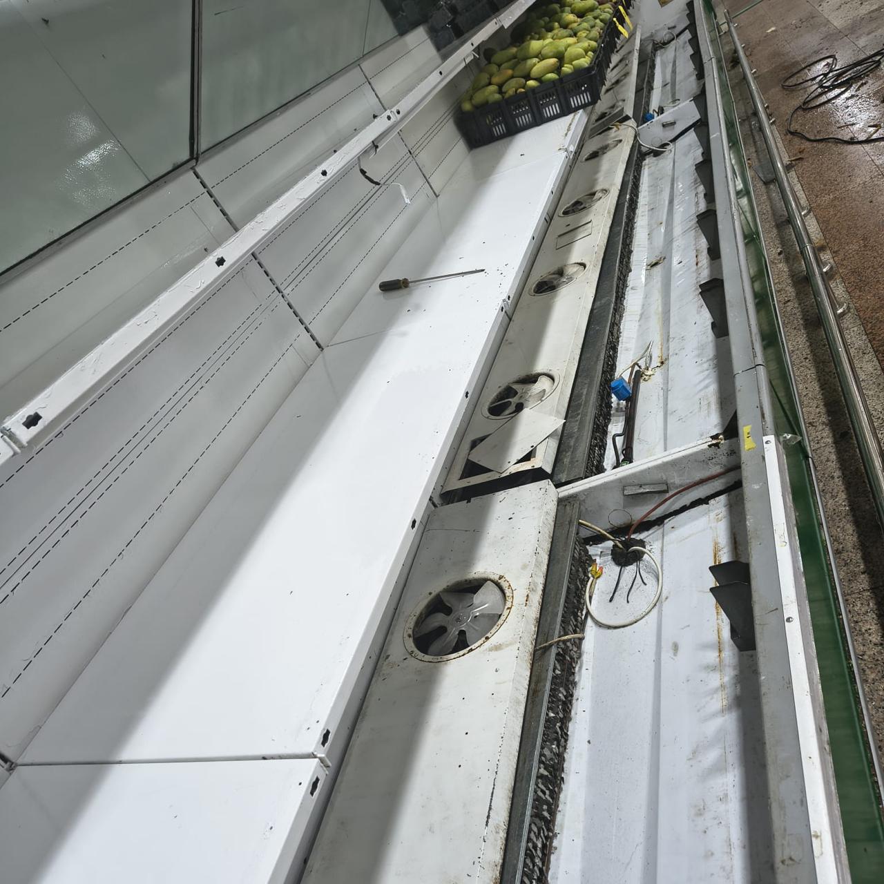 Produce display case stripped down for maintenance with deck panels lifted and evaporator fans exposed